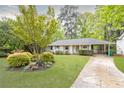 Inviting white brick home featuring lush landscaping and a stone driveway at 1295 Lindenwood Ne Ln, Brookhaven, GA 30319