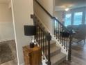 Carpeted staircase with dark metal railings leading to a cozy living room with lots of light at 586 Rodeo Dr, Auburn, GA 30102
