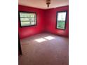 Bedroom with vibrant red walls, natural light streaming in from two windows, and hardwood floors at 1099 Warren Dr, Riverdale, GA 30296