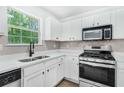 Bright kitchen featuring white cabinets, stainless steel appliances, gray backsplash, and a window at 3487 Creekview Dr, Rex, GA 30273
