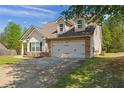 Charming home featuring a two-car garage, stone accents, dormer windows, and a well-manicured lawn at 704 Williamsburg Ct, Villa Rica, GA 30180