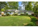 Beautifully landscaped front yard with lush green grass, mature trees, and a charming white exterior at 568 Timberland Dr, Atlanta, GA 30342