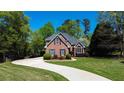 Attractive brick home features a curved driveway, manicured lawn, and mature trees, offering a serene setting at 2319 Lochinver Ln, Conyers, GA 30094