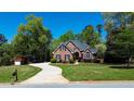 Inviting brick home boasts a winding driveway, lush lawn, mature trees, and a well-maintained landscape at 2319 Lochinver Ln, Conyers, GA 30094