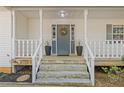 Inviting front porch with stone steps, potted plants, wreath, and white columns creating a warm entrance at 2315 Fisher Dr, Loganville, GA 30052