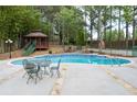 Inviting outdoor pool and gazebo surrounded by lush greenery and a decorative stone border at 5300 Coacoochee Ter, Johns Creek, GA 30022