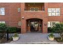 Elegant brick building entrance featuring an arched doorway, lush greenery, and a welcoming pathway at 273 12Th Ne St # 114, Atlanta, GA 30309