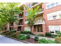 Beautiful brick condo building showcasing multiple balconies, a tree-lined street, and meticulously landscaped gardens at 273 12Th Ne St # 114, Atlanta, GA 30309