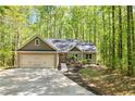 A beautifully landscaped home, featuring a two-car garage, with mature trees providing privacy and a scenic backdrop at 191 Orchard Dr, Canton, GA 30115