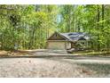 Inviting single-story home with a two-car garage, surrounded by a dense forest backdrop, accessible via a long concrete driveway at 191 Orchard Dr, Canton, GA 30115