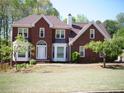 Charming two-story brick home with a well-maintained lawn and mature trees at 4909 Farm Valley Ne Dr, Woodstock, GA 30188