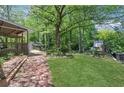 Serene backyard featuring a covered deck and mature trees, offering privacy and shade at 115 Braided Blanket Blf, Johns Creek, GA 30022