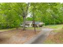 Scenic view of the property featuring a long driveway leading to a charming home surrounded by lush trees at 1943 Scott Rd, Canton, GA 30115