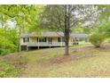 Inviting exterior view of the home featuring a covered porch and set amidst a serene, wooded landscape at 1943 Scott Rd, Canton, GA 30115