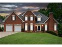 Charming brick home with a well-manicured lawn and a two-car garage at dusk at 3110 Royal Troon, Woodstock, GA 30189