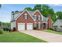 Beautiful red brick home with a 2-car garage and green lawn at 3110 Royal Troon, Woodstock, GA 30189