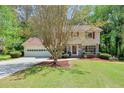 Suburban home with well-kept lawn, mature trees, and inviting curb appeal showing a two-car garage and front door at 1423 Fairfield Sw Dr, Lilburn, GA 30047