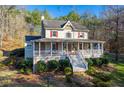 Inviting two-story home with a charming front porch, red shutters, and a well-maintained lawn at 1660 Maple Ridge Dr, Loganville, GA 30052