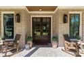 A welcoming front entrance features a brick porch, rocking chairs, potted plants, and elegant lighting fixtures at 284 Hook St, Alpharetta, GA 30009