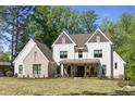 Beautiful home exterior with manicured lawn, white siding, brick accents, and rocking chairs on a covered front porch at 284 Hook St, Alpharetta, GA 30009