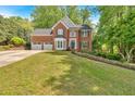 Charming brick home with lush green lawn, two-car garage, and mature trees at 4380 Laurian Nw Dr, Kennesaw, GA 30144