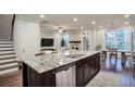 Open-concept kitchen island with stainless steel dishwasher, granite countertops, and view of the living room and dining area at 5022 Towneship Creek Rd, Roswell, GA 30075
