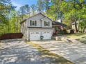 View of the beautiful gray house with a two-car garage, inviting front porch and driveway lined with trees at 363 Ridge Run Dr, Hiram, GA 30141