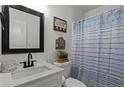 Clean bathroom with a vanity, mirror, toilet, and shower with a blue and white striped curtain at 220 Rocky Point Rd, Covington, GA 30014