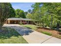 Traditional brick home featuring a spacious driveway and a lush, green front yard with mature trees at 1110 Tuxedo Dr, Roswell, GA 30075