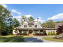 Charming home with a manicured front lawn, mature landscaping, and a welcoming facade with a covered entry at 7305 Breeze Bay Rd, Cumming, GA 30041