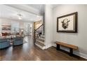 Welcoming entryway featuring hardwood floors, staircase, and a charming bench with decorative art piece at 118 Brighton Blvd, Woodstock, GA 30188