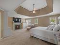 Spacious main bedroom suite features a cozy fireplace, and a tray ceiling with a ceiling fan at 3544 Candytuft Run, Auburn, GA 30011