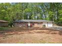 Single story brick home with red shutters and a two car garage, nestled in a wooded location at 5935 Christopher Ln, Lithonia, GA 30058
