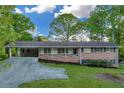 Inviting brick home featuring a convenient carport and a quaint front porch at 2027 Kensington High Sw St, Lilburn, GA 30047