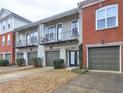 A row of townhouses featuring light gray brick and balconies with attached single-car garages at 5883 Brookside Oak Cir, Norcross, GA 30093
