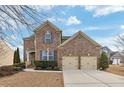 Traditional brick home featuring a two-car garage and manicured landscaping creating curb appeal at 213 Roseman Way, Woodstock, GA 30188