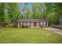 Single-story brick home featuring a well-maintained lawn and mature trees at 2962 Invermere Woods Ct, Lithonia, GA 30038