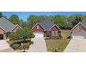 Aerial view of a red brick home with a driveway, tidy lawn, and mature trees on a sunny day at 1610 Glenhurst Dr, Snellville, GA 30078