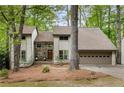 Inviting two-story home with stone accents, a two-car garage, and mature trees surrounding the property at 9295 Martin Rd, Roswell, GA 30076