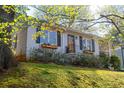 Bungalow with painted gray brick and black shutters with a naturally landscaped hillside at 1763 Delaware Ne Ave, Atlanta, GA 30307