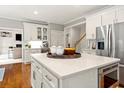 A kitchen island featuring white countertops, cabinets, and stainless steel appliances at 1315 Woodland Trce, Cumming, GA 30041
