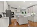 Spacious kitchen featuring white cabinets, stainless appliances, an island, and beautiful hardwood floors at 1315 Woodland Trce, Cumming, GA 30041