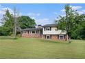 Classic two-story home featuring a brick facade, black shutters, and a spacious lawn with mature trees at 1548 Highway 81 W, Mcdonough, GA 30253