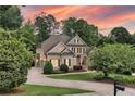 Two-story home surrounded by mature trees with a well-maintained lawn and inviting driveway, set against a sunset sky at 330 Plantation Way, Roswell, GA 30075