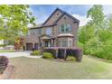 Two-story brick home featuring manicured lawn, decorative shrubs, and a two-car garage at 3097 Trinity Grove Dr, Dacula, GA 30019