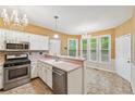 Open kitchen with stainless steel appliances, pink countertops, and a chandelier lighting at 10044 Point View Dr, Jonesboro, GA 30238