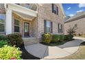 Inviting entrance showcasing a stone pathway leading to a brick home with dark shutters and trim at 6090 Pennant Ln, Suwanee, GA 30024