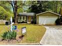 Lovely house with a lush front yard, showing a 'For Sale' sign, and a convenient driveway leading to the garage at 921 Hemingway Rd, Stone Mountain, GA 30088