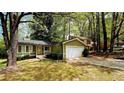 Charming home with green siding, a cozy front porch, and an attached garage surrounded by lush trees at 921 Hemingway Rd, Stone Mountain, GA 30088
