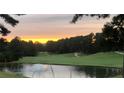 Scenic view of the golf course, with a water feature in the foreground, lush trees, and a beautiful sunset sky at 71 Tobinleigh Ct, Acworth, GA 30101
